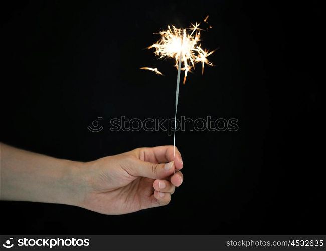 christmas, holidays, new year party and pyrotechnics concept - male hand holding sparkler or bengal light burning over black background