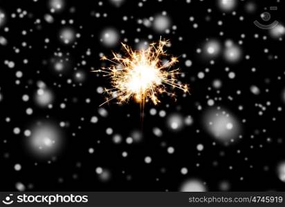 christmas, holidays, new year party and pyrotechnics concept - sparkler or bengal light burning over black background with snow