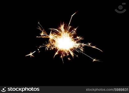 christmas, holidays, new year party and pyrotechnics concept - sparkler or bengal light burning over black background