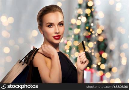 christmas, holidays, people, luxury and sale concept - beautiful woman with credit card and shopping bags over lights background