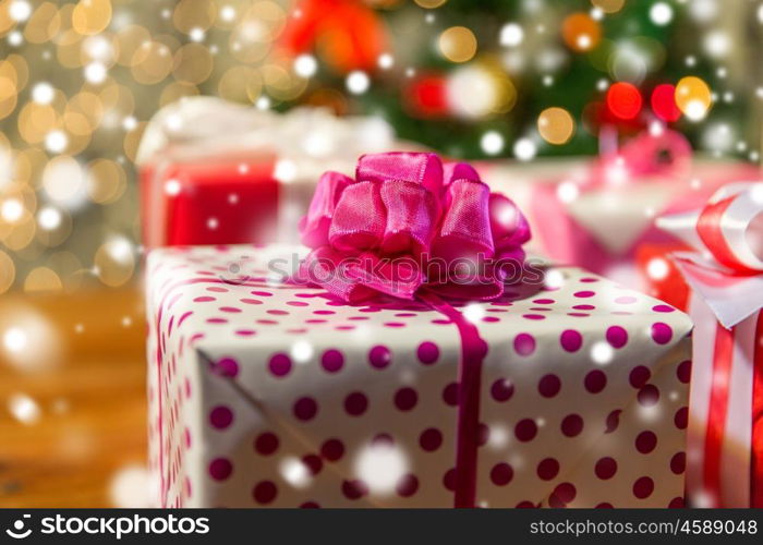 christmas, holidays, presents, new year and celebration concept - close up of gift boxes over christmas tree lights