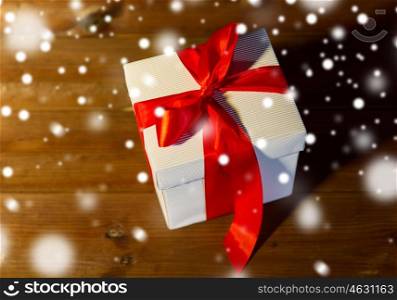 christmas, holidays, presents, new year and celebration concept - close up of gift box with red bow on wooden floor from top