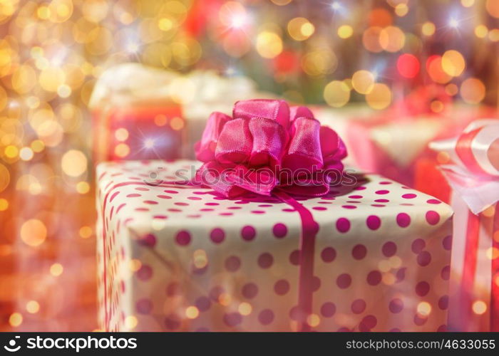 christmas, holidays, presents, new year and celebration concept - close up of gift boxes over christmas tree lights