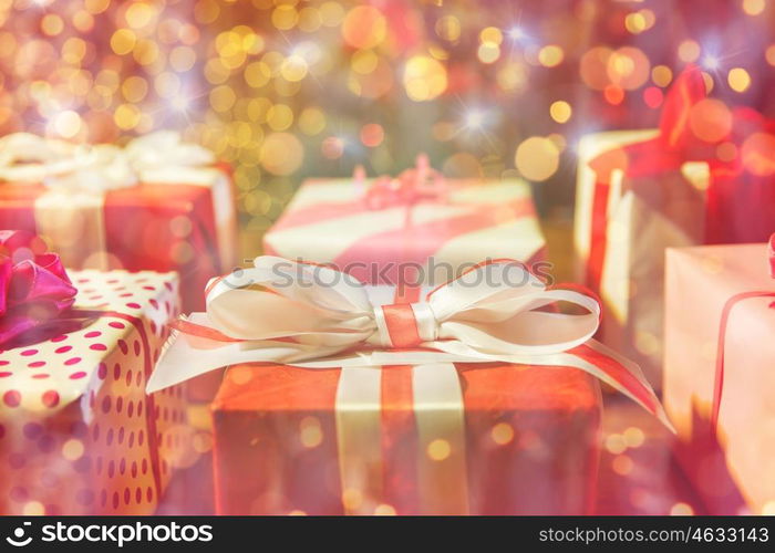 christmas, holidays, presents, new year and celebration concept - close up of gift boxes over christmas lights