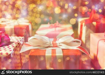 christmas, holidays, presents, new year and celebration concept - close up of gift boxes over christmas lights