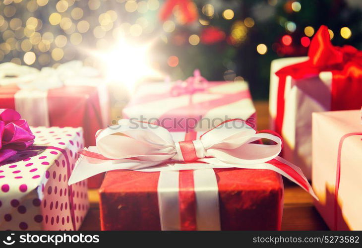 christmas, holidays, presents, new year and celebration concept - close up of gift boxes over christmas tree lights. close up of gift boxes over christmas tree lights