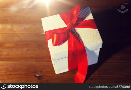 christmas, holidays, presents, new year and celebration concept - close up of gift box with red bow on wooden floor from top. close up of christmas gift box on wooden floor