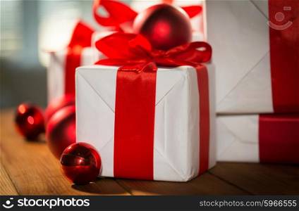 christmas, holidays, presents, new year and celebration concept - close up of gift boxes and red balls on wooden floor