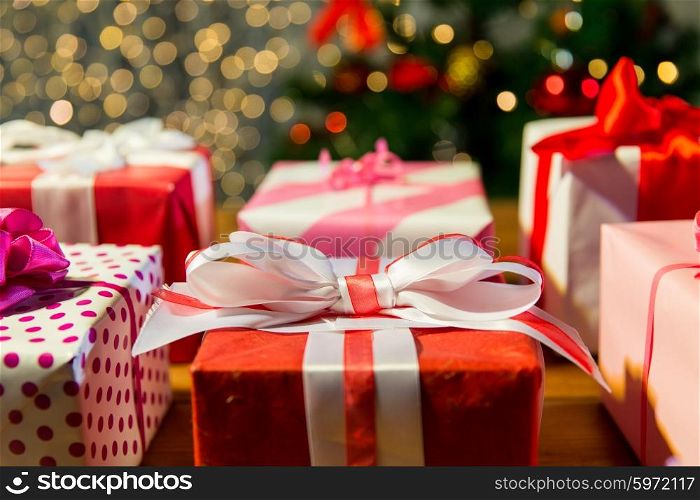 christmas, holidays, presents, new year and celebration concept - close up of gift boxes over christmas tree lights