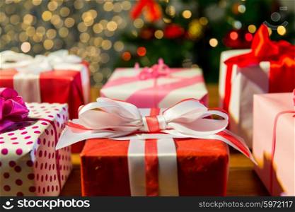christmas, holidays, presents, new year and celebration concept - close up of gift boxes over christmas tree lights