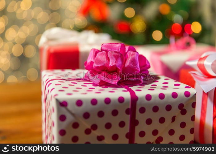 christmas, holidays, presents, new year and celebration concept - close up of gift boxes over christmas tree lights