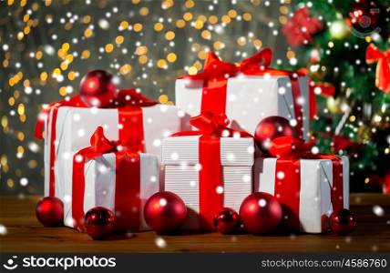 christmas, holidays, presents, new year and celebration concept - group of gift boxes and red balls under x-mas tree on wooden floor