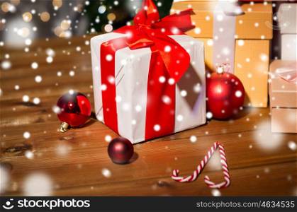christmas, holidays, presents, new year and celebration concept - group of gift boxes and red balls on wooden board over lights