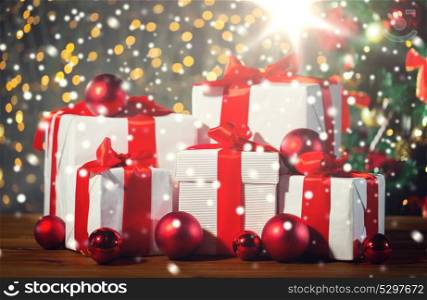 christmas, holidays, presents, new year and celebration concept - group of gift boxes and red balls under x-mas tree on wooden floor. gift boxes and red balls under christmas tree