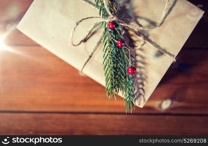 christmas, holidays, presents, new year and decor concept - close up of gift box wrapped into brown mail paper and decorated with fir brunch and rope bow. close up of christmas gift box with fir brunch