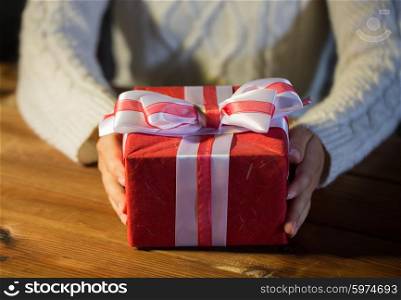 christmas, holidays, presents, new year and people concept - close up of woman hands holding gift box decorated with bow