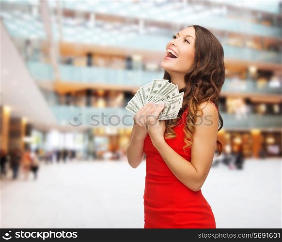 christmas, holidays, sale, banking and people concept - smiling woman in red dress with us dollar money over shopping center background