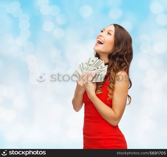 christmas, holidays, sale, banking and people concept - smiling woman in red dress with us dollar money over blue lights background