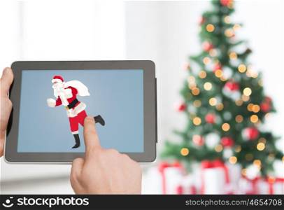 christmas, holidays, technology and people concept - close up of man hands with santa claus picture on tablet pc computer screen