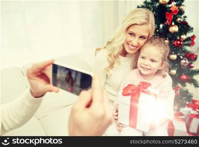 christmas, holidays, technology and people concept - happy family sitting on sofa and taking picture with smartphone at home. family taking picture with smartphone at christmas