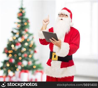 christmas, holidays, technology and people concept - man in costume of santa claus with tablet pc computer pointing finger up over living room with tree background