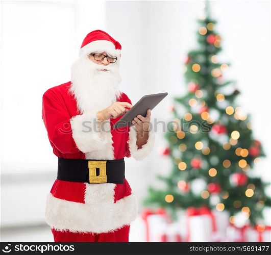 christmas, holidays, technology and people concept - man in costume of santa claus with tablet pc computer over living room with tree background