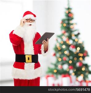 christmas, holidays, technology and people concept - man in costume of santa claus with tablet pc computer over living room with tree background