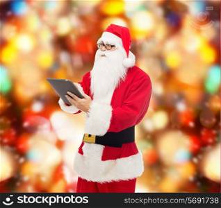 christmas, holidays, technology and people concept - man in costume of santa claus with tablet pc computer over red lights background
