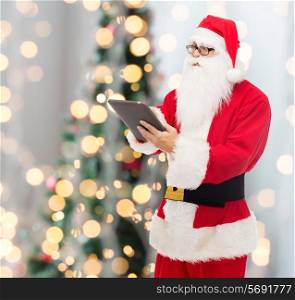 christmas, holidays, technology and people concept - man in costume of santa claus with tablet pc computer over tree lights background