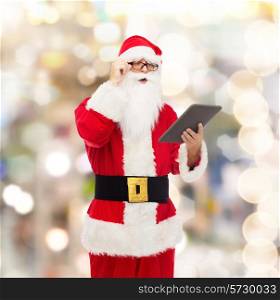 christmas, holidays, technology and people concept - man in costume of santa claus with tablet pc computer over lights background