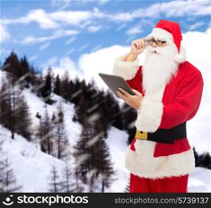 christmas, holidays, technology and people concept - man in costume of santa claus with tablet pc computer over snowy mountains background