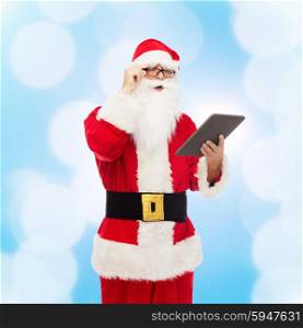 christmas, holidays, technology and people concept - man in costume of santa claus with tablet pc computer over blue lights background