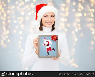 christmas, holidays, technology and people concept - smiling woman holding tablet pc computer with santa claus picture on screen over lights background
