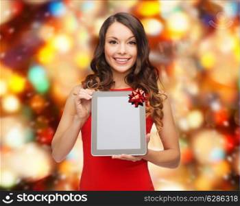 christmas, holidays, technology and people concept - smiling woman in red dress with tablet pc computer over red lights background