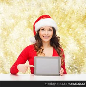 christmas, holidays, technology and people concept - smiling woman in santa helper hat with tablet pc computer over yellow lights background