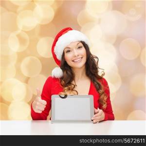 christmas, holidays, technology and people concept - smiling woman in santa helper hat with tablet pc computer showing thumbs up over beige lights background
