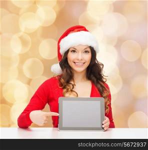 christmas, holidays, technology and people concept - smiling woman in santa helper hat with tablet pc computer over beige lights background