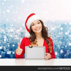 christmas, holidays, technology and people concept - smiling woman in santa helper hat with tablet pc computer showing thumbs up over snowy city background