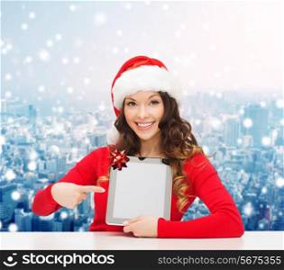 christmas, holidays, technology and people concept - smiling woman in santa helper hat with tablet pc computer over snowy city background