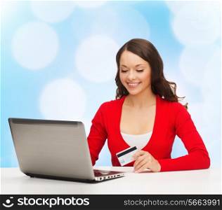 christmas, holidays, technology and shopping concept - smiling woman with credit card and laptop computer over blue lights background