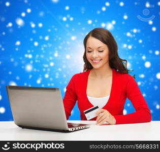 christmas, holidays, technology and shopping concept - smiling woman with credit card and laptop computer over blue snowing background