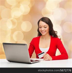 christmas, holidays, technology and shopping concept - smiling woman with credit card and laptop computer over beige lights background