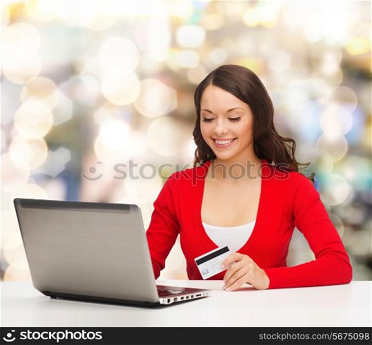 christmas, holidays, technology and shopping concept - smiling woman with credit card and laptop computer over lights background