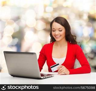 christmas, holidays, technology and shopping concept - smiling woman with credit card and laptop computer over lights background
