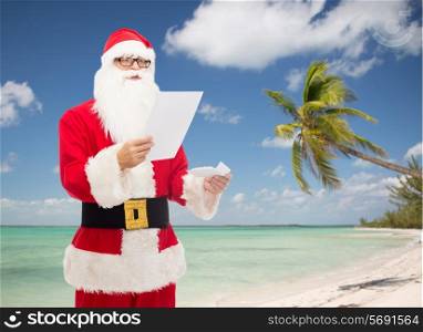 christmas, holidays, travel and people concept - man in costume of santa claus reading letter