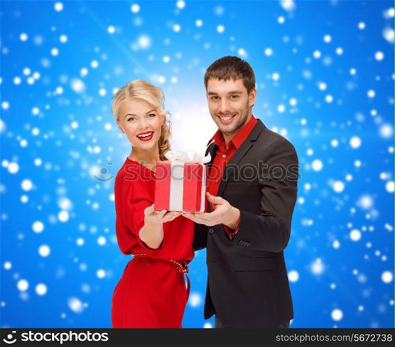 christmas, holidays, valentine&#39;s day, celebration and people concept - smiling man and woman with present over blue snowy background