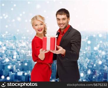 christmas, holidays, valentine&#39;s day, celebration and people concept - smiling man and woman with present over snowy city background