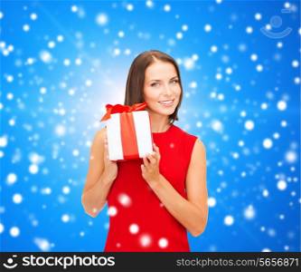 christmas, holidays, valentine&#39;s day, celebration and people concept - smiling woman in red dress with gift box over blue snowy background