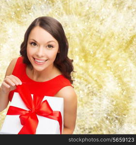 christmas, holidays, valentine&#39;s day, celebration and people concept - smiling woman in red dress with gift box over yellow lights background