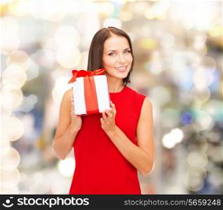 christmas, holidays, valentine&#39;s day, celebration and people concept - smiling woman in red dress with gift box over lights background